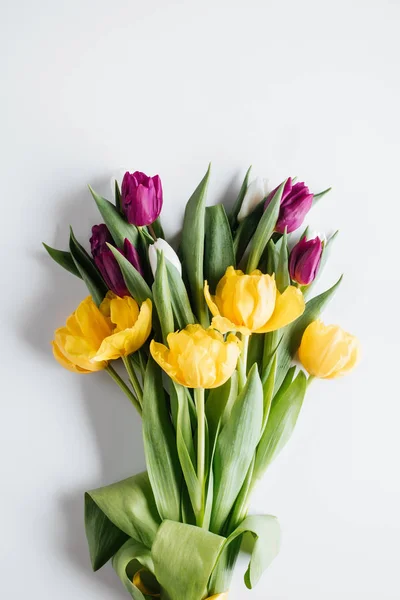 Vista superior del ramo de tulipanes morados y amarillos sobre blanco - foto de stock