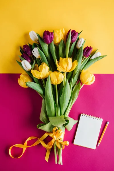 Top view of spring tulips with notepad and pencil for international womens day — Stock Photo