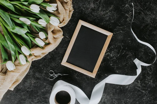 Верхний вид белых тюльпанов, лента и рамка на черной поверхности, 8 мартовский фон — стоковое фото