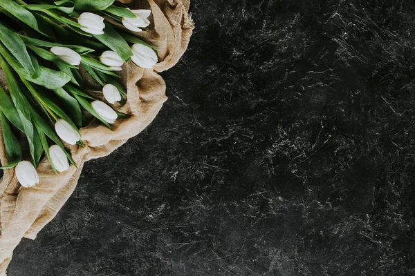 Top view of white tulip flowers on tablecloth on black surface — Stock Photo