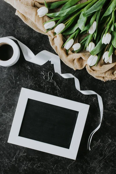 Draufsicht auf weiße Tulpen, Band und Rahmen auf schwarzer Oberfläche, Hintergrund zum Internationalen Frauentag — Stockfoto