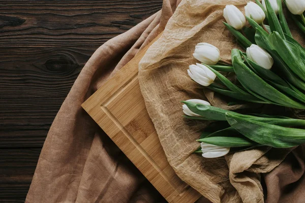 Vue de dessus des tulipes de printemps sur la nappe et le conseil en bois pour la journée internationale des femmes — Photo de stock