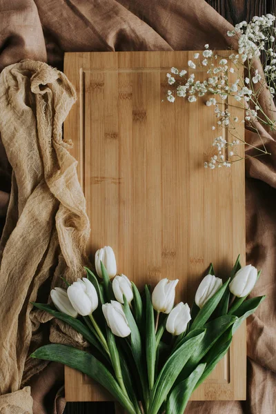 Top view of white tulips on wooden board and tablecloth for international womens day — Stock Photo