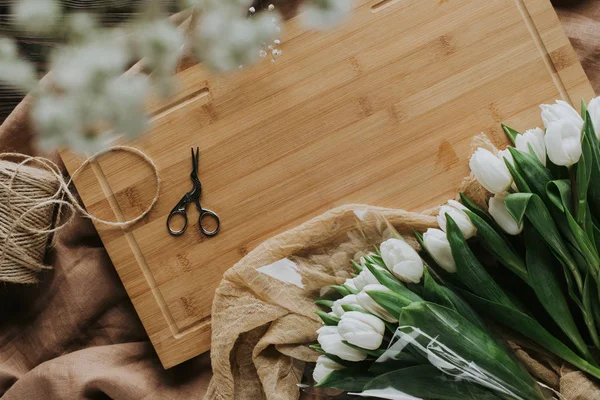 Vista superior de tulipanes blancos, tijeras y cordel en tablero de madera para 8 marzo - foto de stock