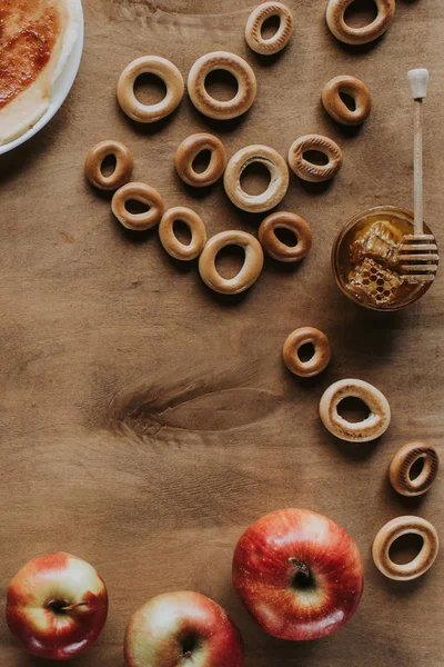 Vista superior de bagels doces, mel e maçãs na mesa de madeira — Fotografia de Stock