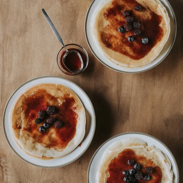 Top view of sweet homemade pancakes with jam and berries on wooden table — Stock Photo