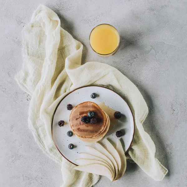 Vue de dessus de délicieuses crêpes maison avec des fruits frais et un verre de jus sur gris — Photo de stock