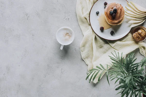 Vista superior de panquecas saborosas doces com bagas e cappuccino em cinza — Fotografia de Stock