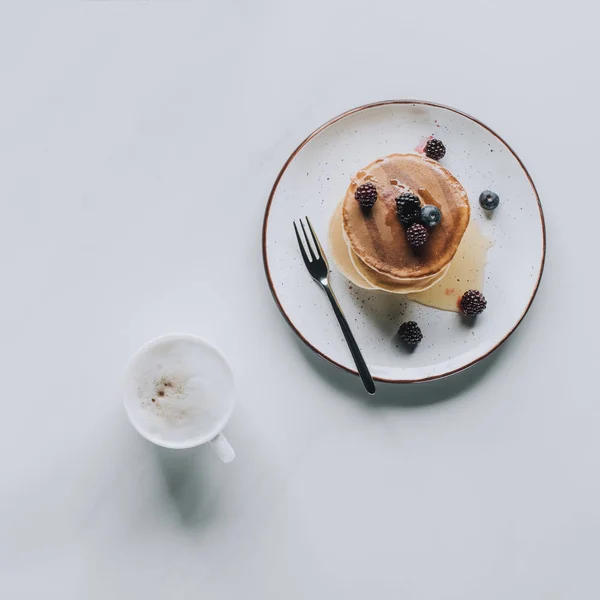 Vista dall'alto di gustose frittelle salutari e tazza di cappuccino su grigio — Foto stock