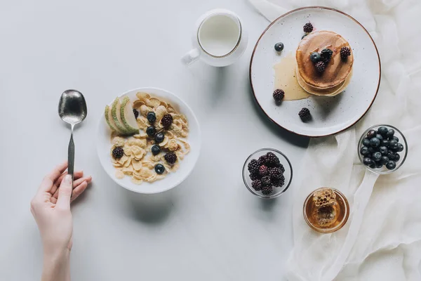 Abgeschnittene Aufnahme einer Person mit Löffel und frischem gesunden Frühstück auf grau — Stockfoto