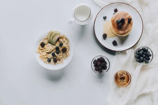 Top view of fresh healthy muesli with pancakes and fruits on grey — Stock Photo