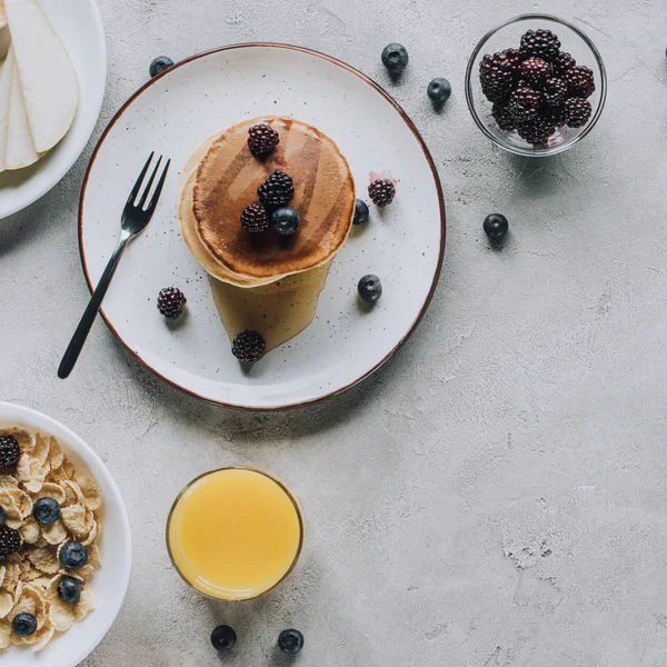 Vista superior de deliciosas panquecas caseiras, copo de suco e muesli em cinza — Fotografia de Stock