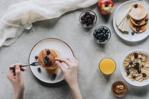 Tiro cortado de pessoa comendo deliciosas panquecas caseiras com bagas para o café da manhã — Fotografia de Stock