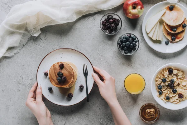 Blick von oben auf Person, die leckere hausgemachte Pfannkuchen mit Beeren zum Frühstück isst — Stockfoto