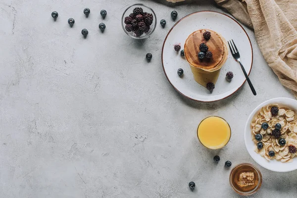 Top view of tasty healthy breakfast with pancakes, berries, honey and muesli on grey — Stock Photo