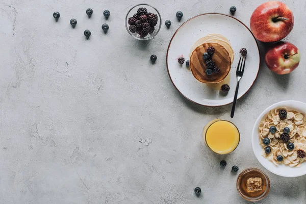 Top view of tasty healthy breakfast with pancakes, fruits, honey and muesli on grey — Stock Photo