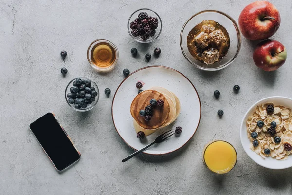 Вид сверху на смартфон с чистым экраном и вкусный здоровый завтрак на сером — стоковое фото