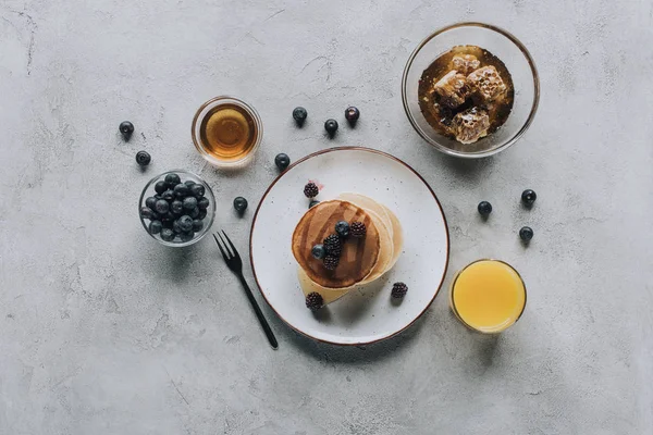 Gourmet-Pfannkuchen mit frischen Beeren, Saft und Honig auf grau — Stockfoto
