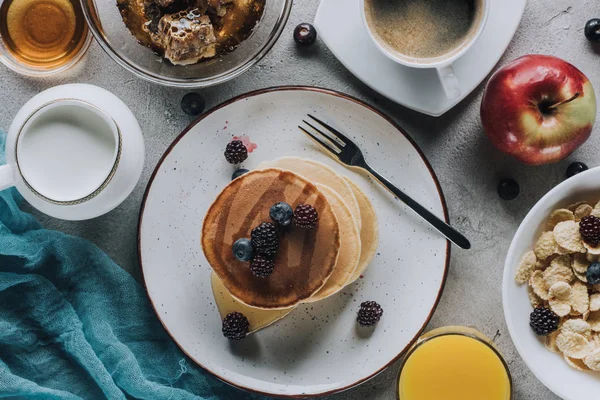 Blick von oben auf leckeres gesundes Frühstück mit Pfannkuchen, Früchten und Müsli auf grau — Stockfoto