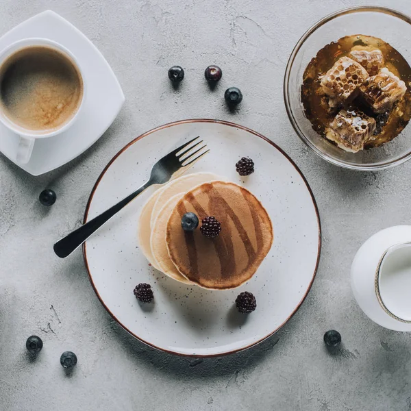 Vista superior de deliciosas panquecas com compota e bagas, café com leite e mel em cinza — Fotografia de Stock