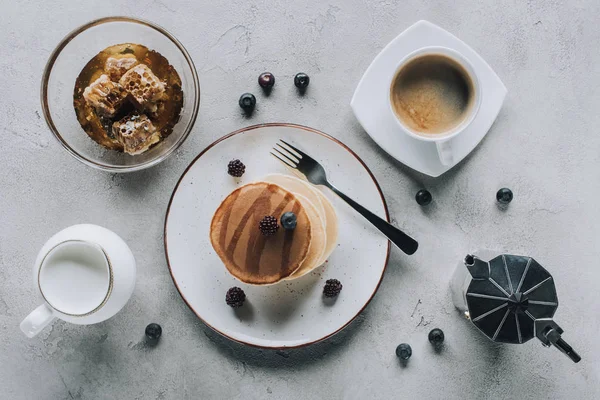 Верхний вид сладких вкусных блинов с кофе, молоком, свежими ягодами и медом на сером — стоковое фото
