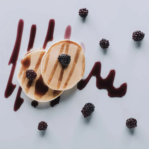 Blick von oben auf leckere süße hausgemachte Pfannkuchen mit frischen Brombeeren und Marmelade auf grau — Stockfoto