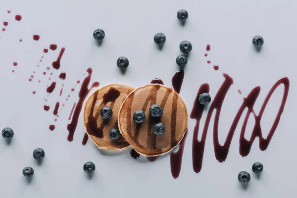 Blick von oben auf leckere Pfannkuchen mit frischen Blaubeeren und Marmelade auf Grau — Stockfoto