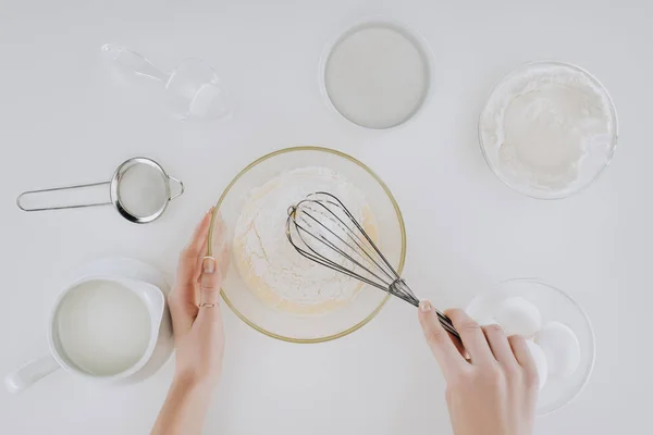 Abgeschnittene Aufnahme einer Person, die Teig verquirlt, während sie Pfannkuchen isoliert auf grau kocht — Stockfoto