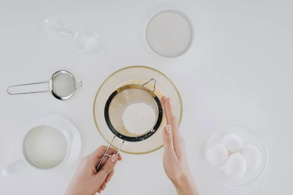 Abgeschnittene Aufnahme einer Person, die beim Kochen von Pfannkuchen Mehl siebte, isoliert auf grau — Stockfoto