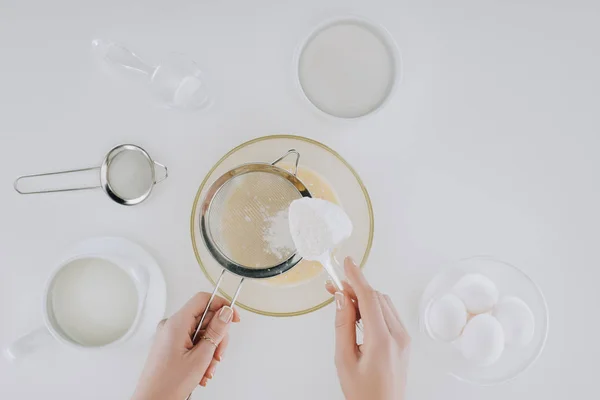 Top view of person sifting flour while cooking pancakes isolated on grey — Stock Photo