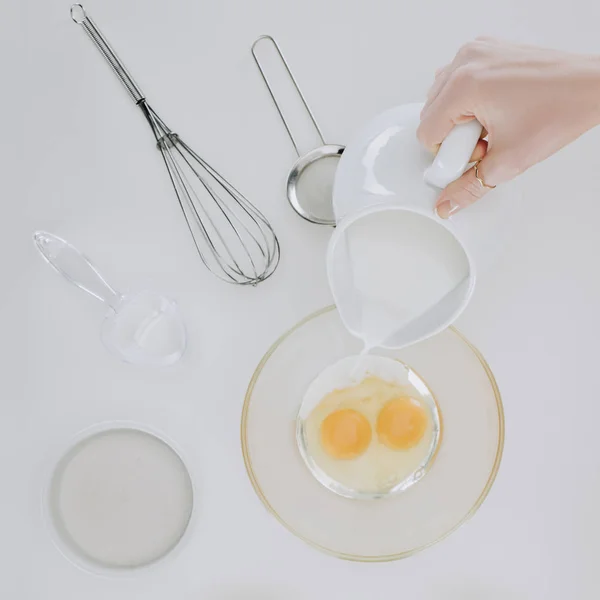 Top view of person pouring milk while cooking pancakes isolated on grey — Stock Photo