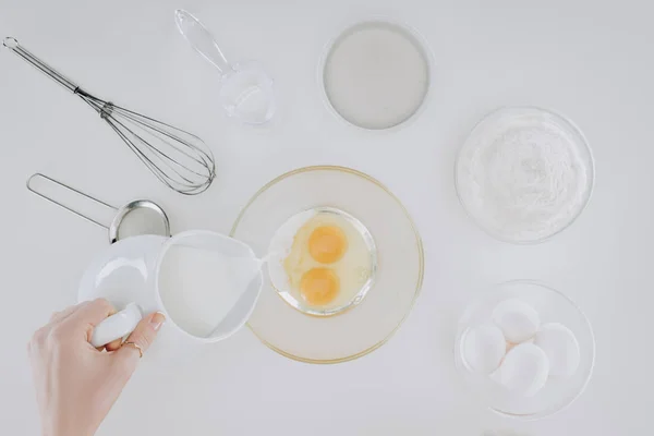 Colpo ritagliato di persona versando il latte durante la cottura frittelle isolate su grigio — Foto stock