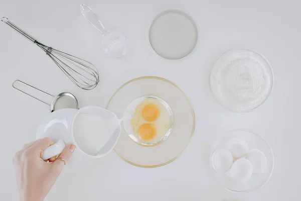 Cropped shot of person pouring milk while cooking pancakes isolated on grey — Stock Photo