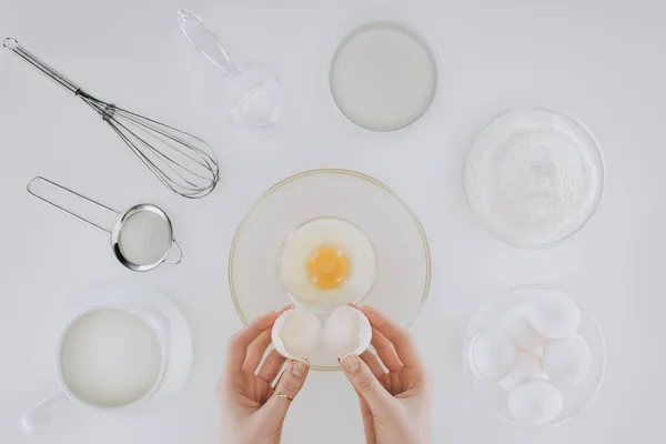 Cliché recadré d'une personne tenant une coquille d'oeuf pendant la cuisson de crêpes isolées sur gris — Photo de stock