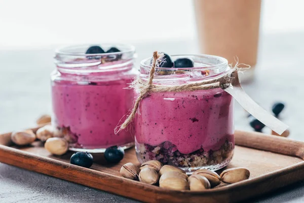 Vista de cerca de batido rosa gourmet saludable con granola, frutos secos y bayas - foto de stock