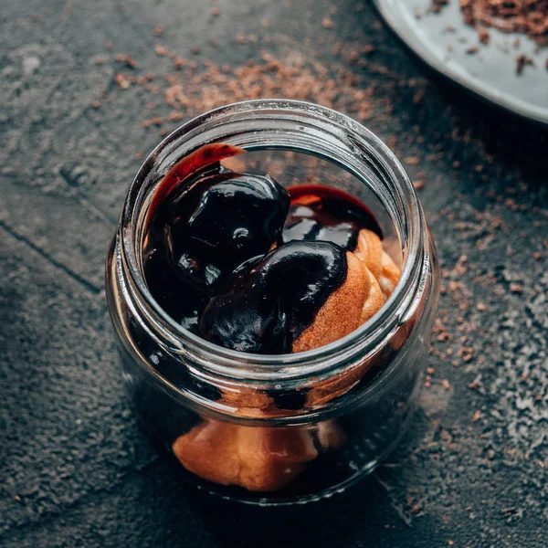 Close-up view of sweet delicious homemade chocolate dessert in glass jar on black — Stock Photo