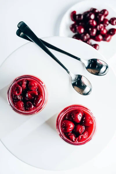 Top view of sweet tasty cherry dessert in glass jars on white — Stock Photo