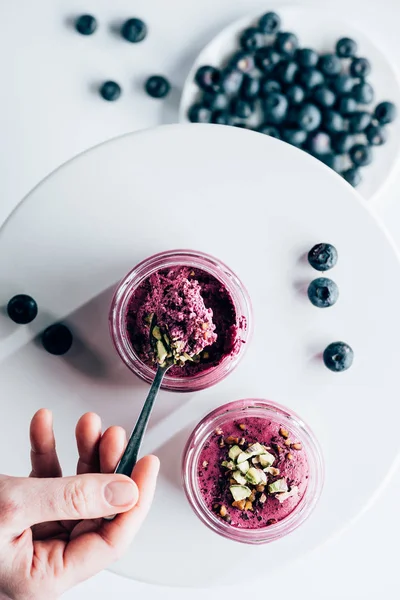 Cropped shot of person eating tasty healthy smoothie with granola and blueberries — Stock Photo