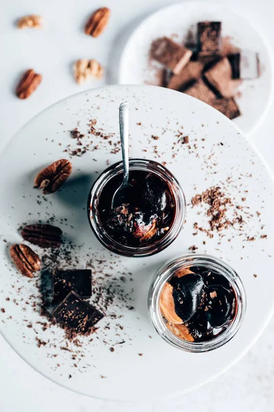 Top view of delicious chocolate dessert in glass jars on white plate with nuts — Stock Photo