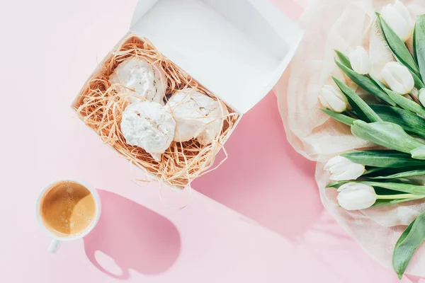 Blick von oben auf weiße Tulpen, köstliche Baiser-Kekse und eine Tasse Kaffee auf rosa — Stockfoto