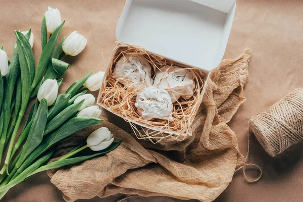Top view of delicious meringue cookies in box and white tulips — Stock Photo