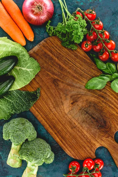 Вид сверху на свежие здоровые сырые овощи и деревянную доску — стоковое фото