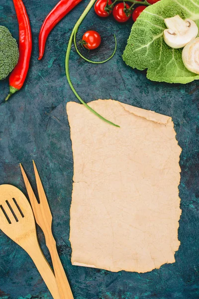 Top view of blank parchment, wooden utensils and ripe raw vegetables on black — Stock Photo