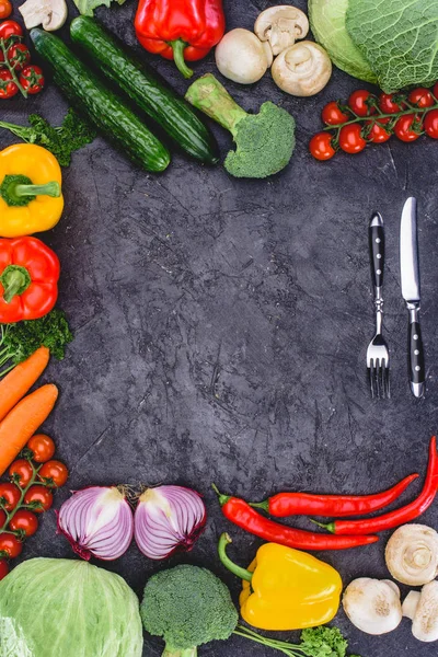Vista superior de verduras orgánicas frescas saludables y tenedor con cuchillo en negro - foto de stock