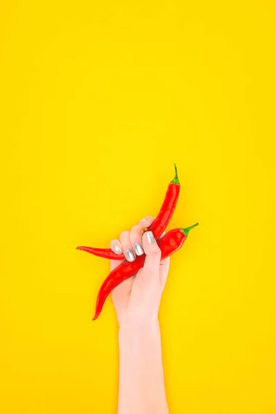 Cropped shot of person holding red chili peppers isolated on yellow — Stock Photo