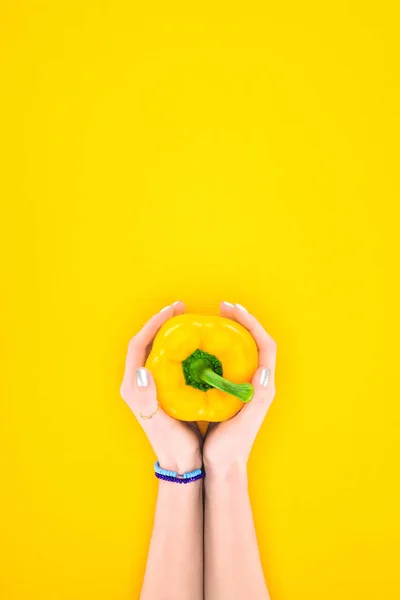 Vue de dessus des mains humaines tenant du poivre bio cru frais isolé sur jaune — Photo de stock