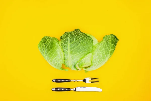 Вид зверху на свіжу здорову капусту і виделку з ножем ізольовано на жовтому — стокове фото
