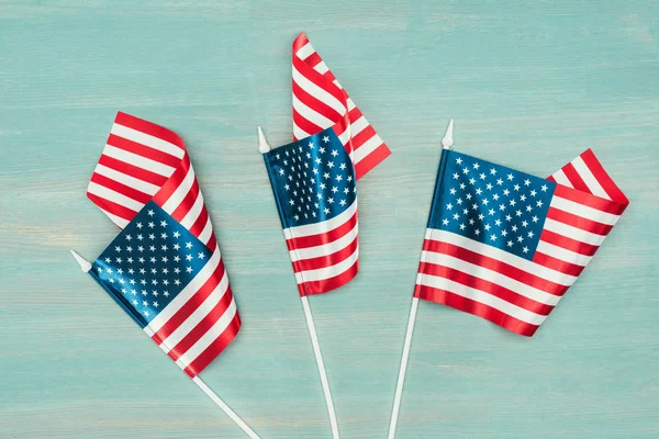 Vista superior de las banderas americanas dispuestas en la superficie azul de madera, concepto de día de presidentes - foto de stock
