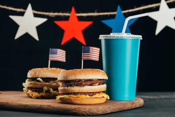 Primer plano vista de hamburguesas con bandera americana y bebida gaseosa, concepto de celebración del día de presidentes - foto de stock
