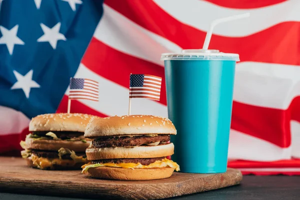 Vista de perto de hambúrgueres com bandeiras americanas e bebida com gás, conceito de celebração do dia dos presidentes — Fotografia de Stock